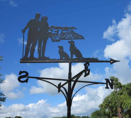 a dog walker themed weathervane, picturing a Couple Walking, Hills And Dogs against a blue sky