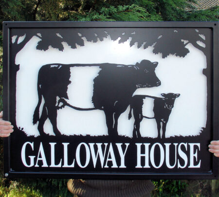 Belted Galloways farm sign with white backing sheet against dark backdrop