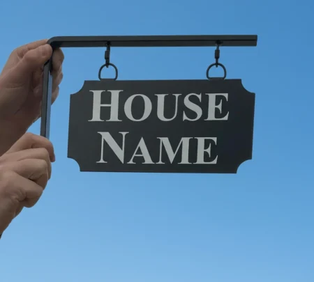 Small Hanging Metal House Name Sign - Scallop Corners Held Up Outside Workshop